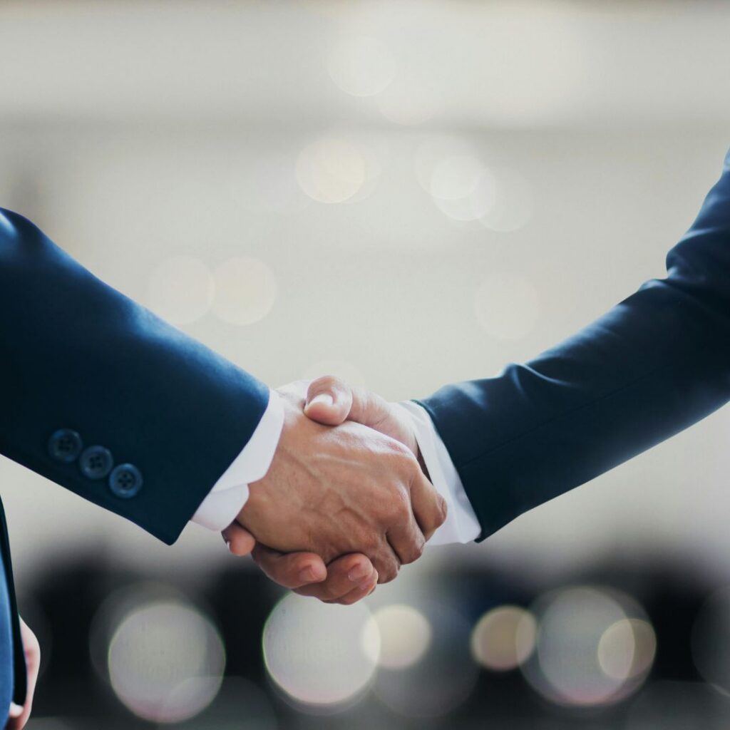 Close-up of two business professionals in dark suits shaking hands.